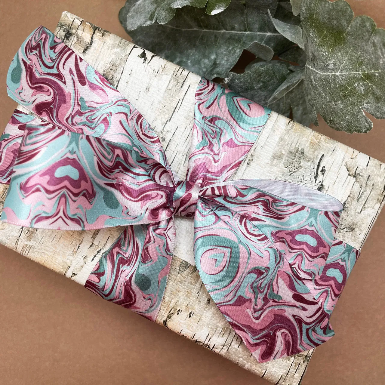 Marbled ribbon in shades of mauve and mint printed on 1.5" white single face satin